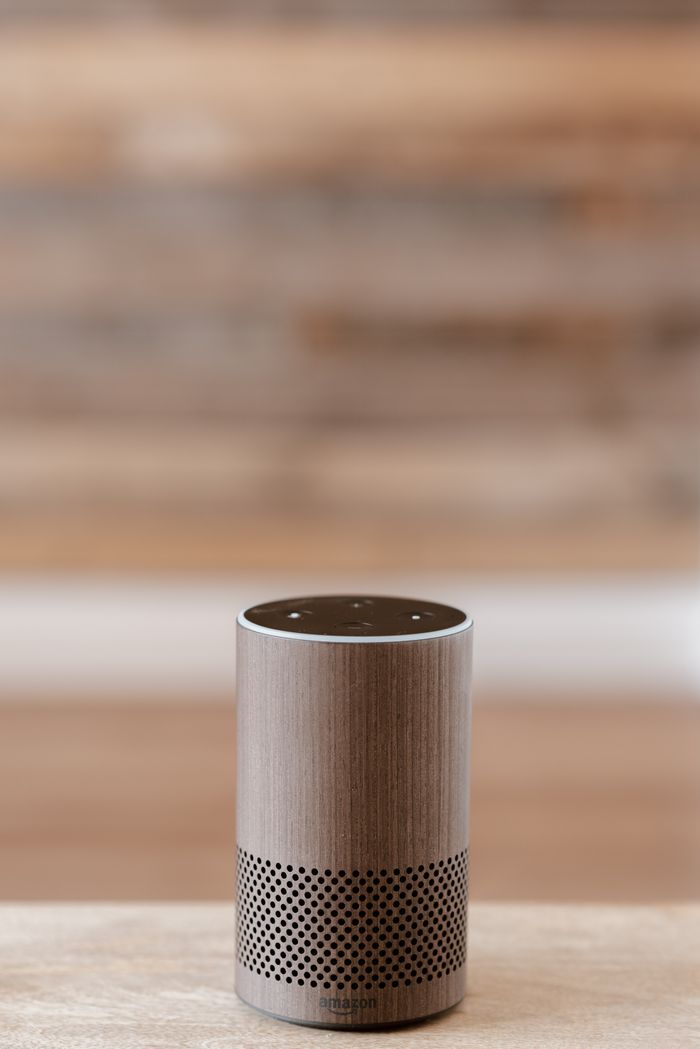 who-we-are A smart speaker placed on a wooden surface against a blurred background, emphasizing minimalist design.
