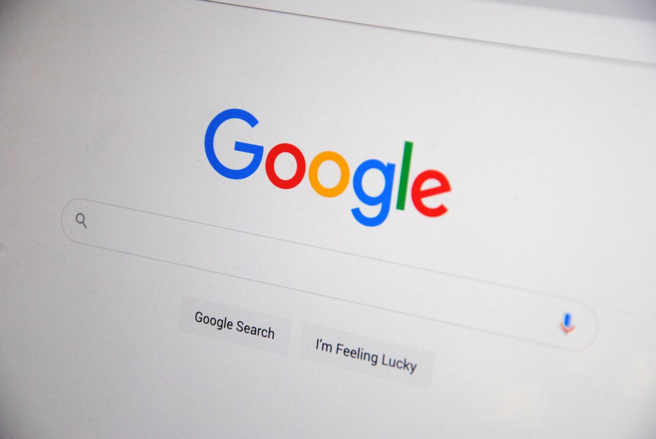 services-03 Close-up of the Google homepage on a screen showing search options.
